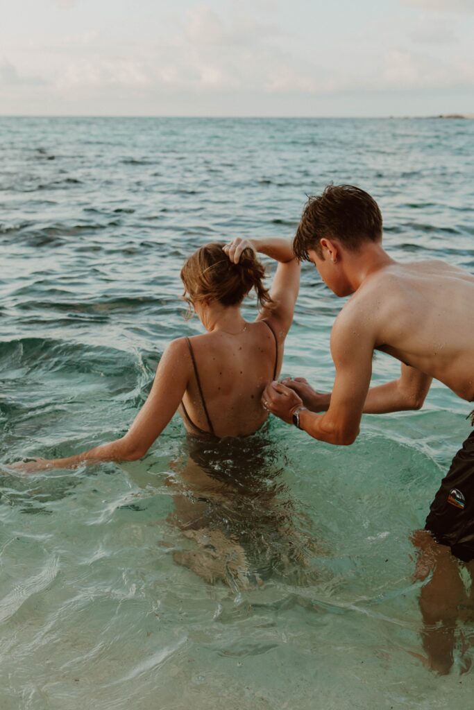 husband squirting water on wife's back in ocean hawaii elopement photographer