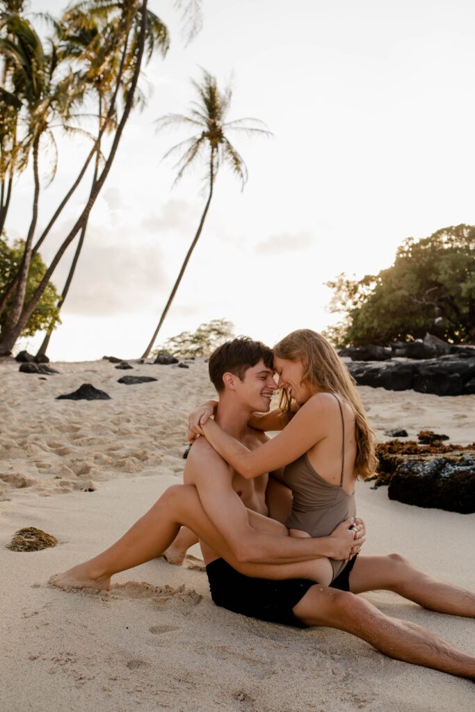 couple hugging each other on beach in front of palm trees Hawaii photographers big island