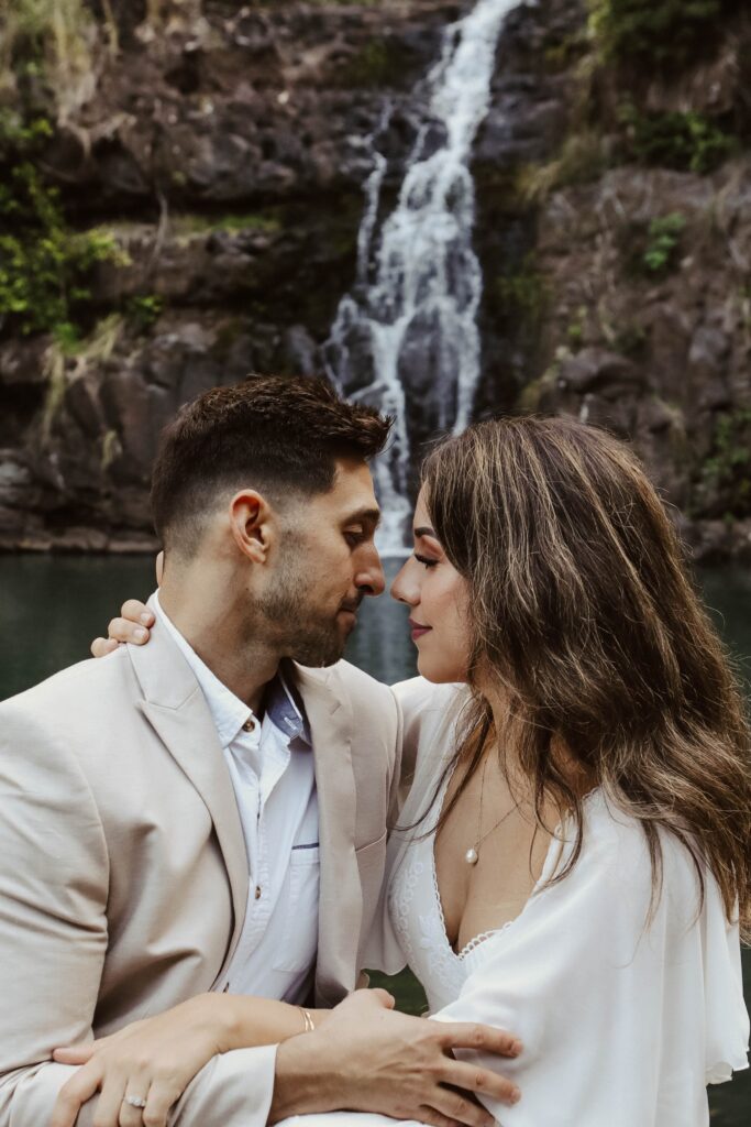 couple holding each other in front of waterfall hawaii adventure elopement 