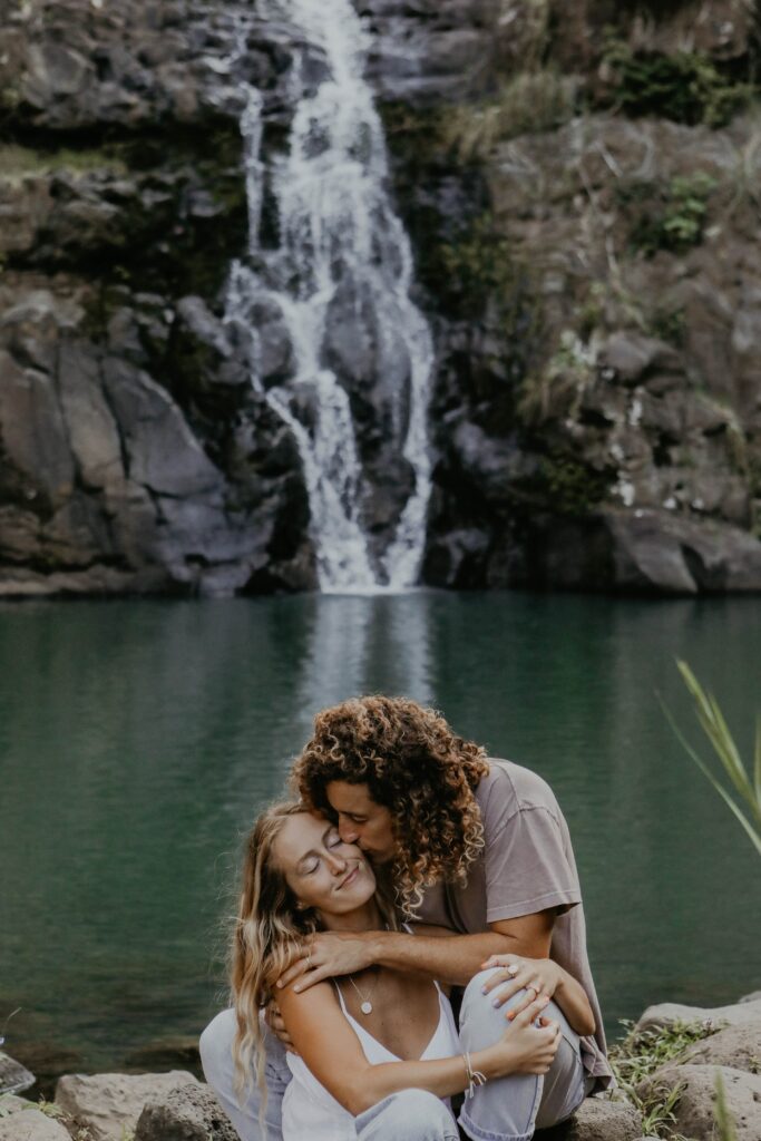 couple kissing in front of waterfall on oahu elopement packages san diego ca