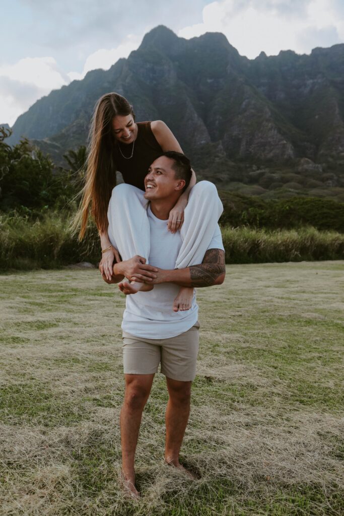 Husband giving wife piggy back ride on front of mountains hawaii elopement photographer 