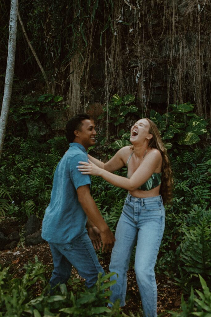 couple laughing and playing in front of a hawaiian jungle bush hawaii elopement photographer packages 