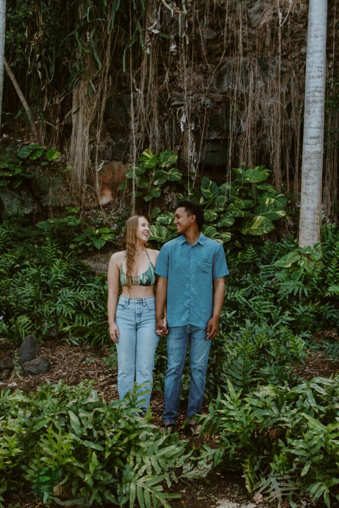 couple standing side by side looking at each other in front of Hawaiian jungle hawaii elopement photographer packages