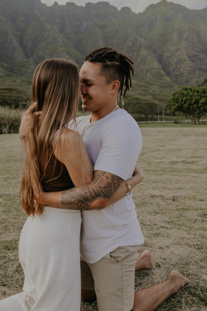 couple embracing each other in front of mountains hawaii engagement