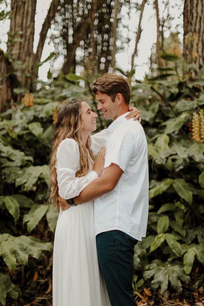 bride and groom hugging in front of a fern bush in hawaii haswaii adventure wedding 