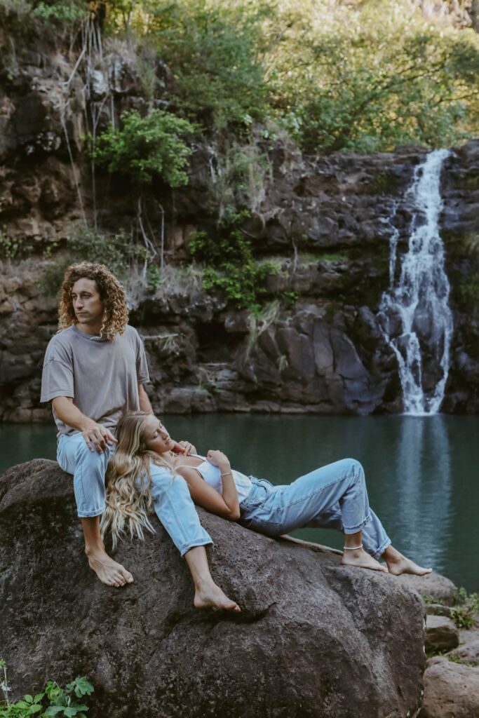 couple relaxing in front of waterfall on rocks in Hawaii Adventure photographer Kauai
