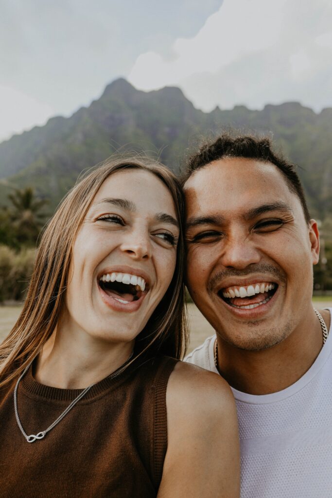 couple laughing with mountains in background Hawaii engagement