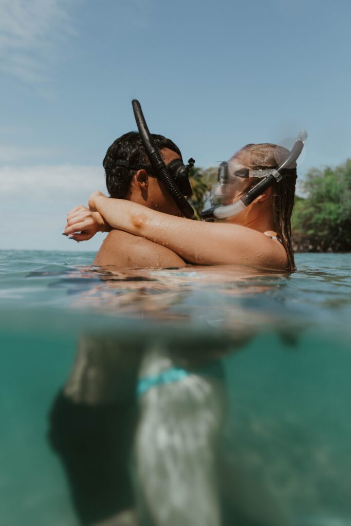 couple hugging in ocean wearing snorkel masks engagement photographer hawaii