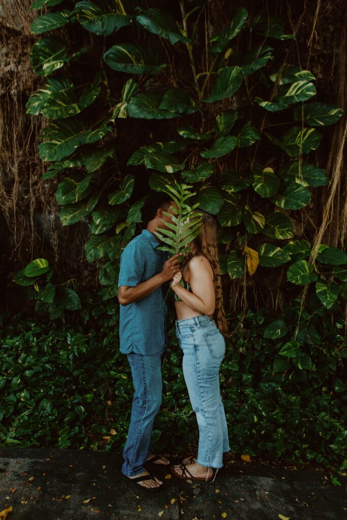 couple kissing behind fern plant hawaii elopement