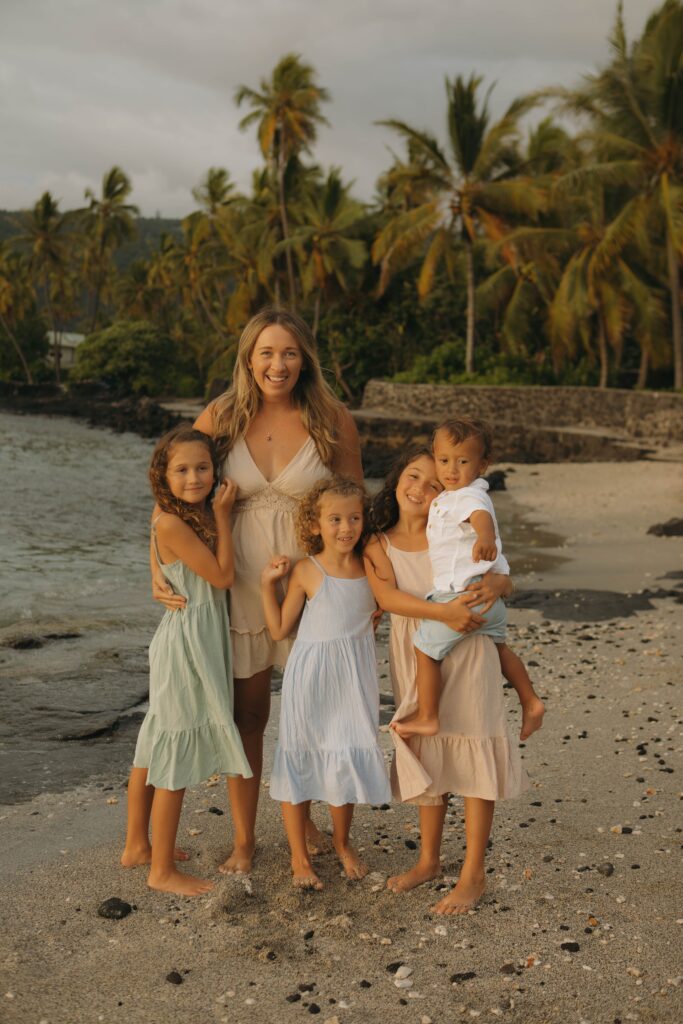 A Mom and her kids smiling at the camera in hawaii on the beach